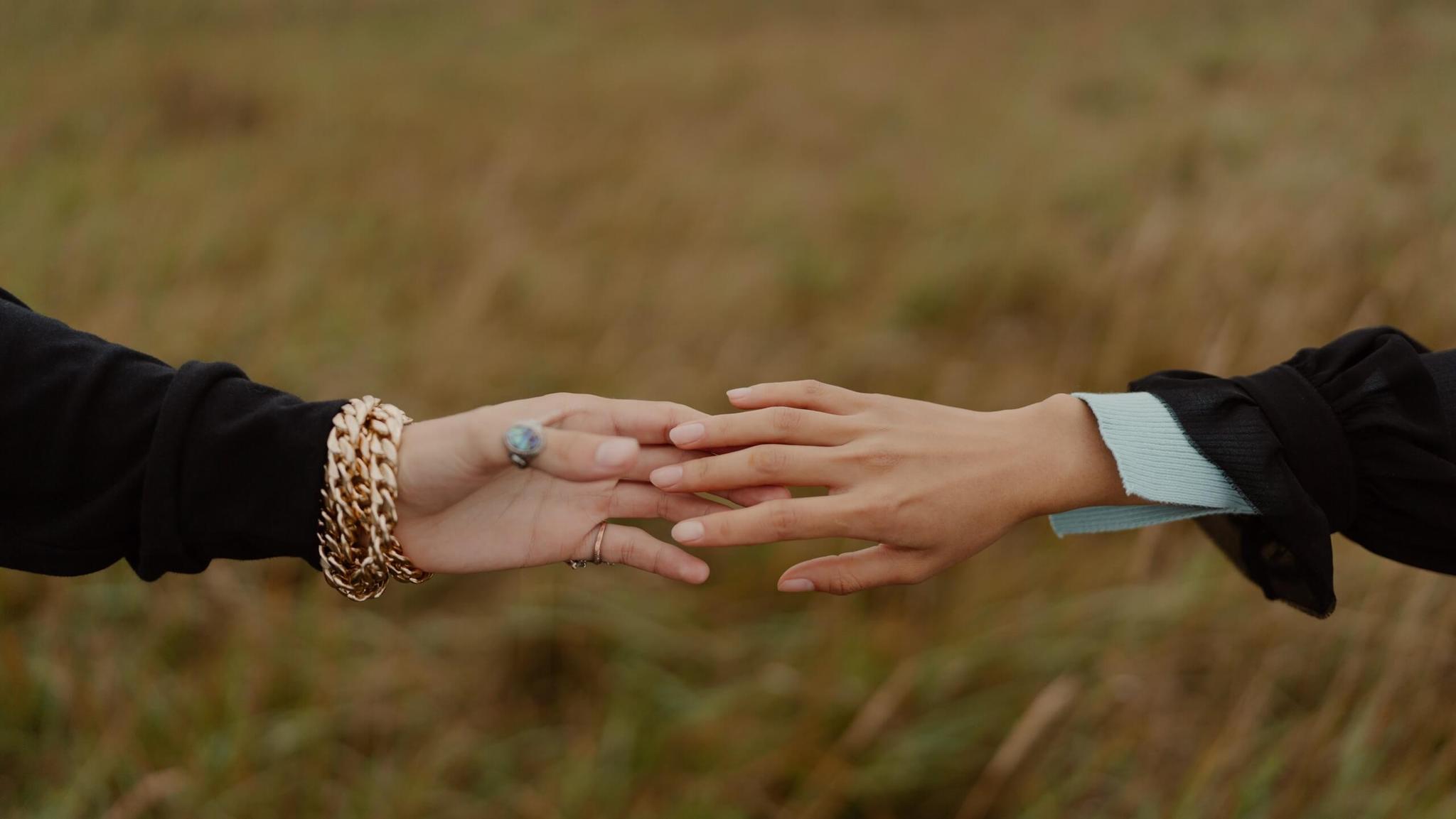 Finger tips touching against a green backdrop. The peoples desire for each other isn't aligned and the are struggling to come together.