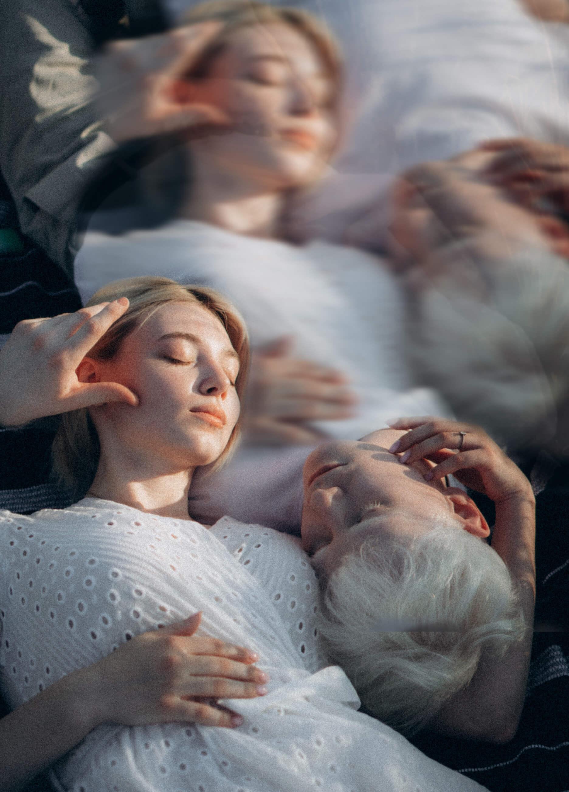 A man and woman lying on their backs with their eye's closed in an ethereal light struggling to communicate.
