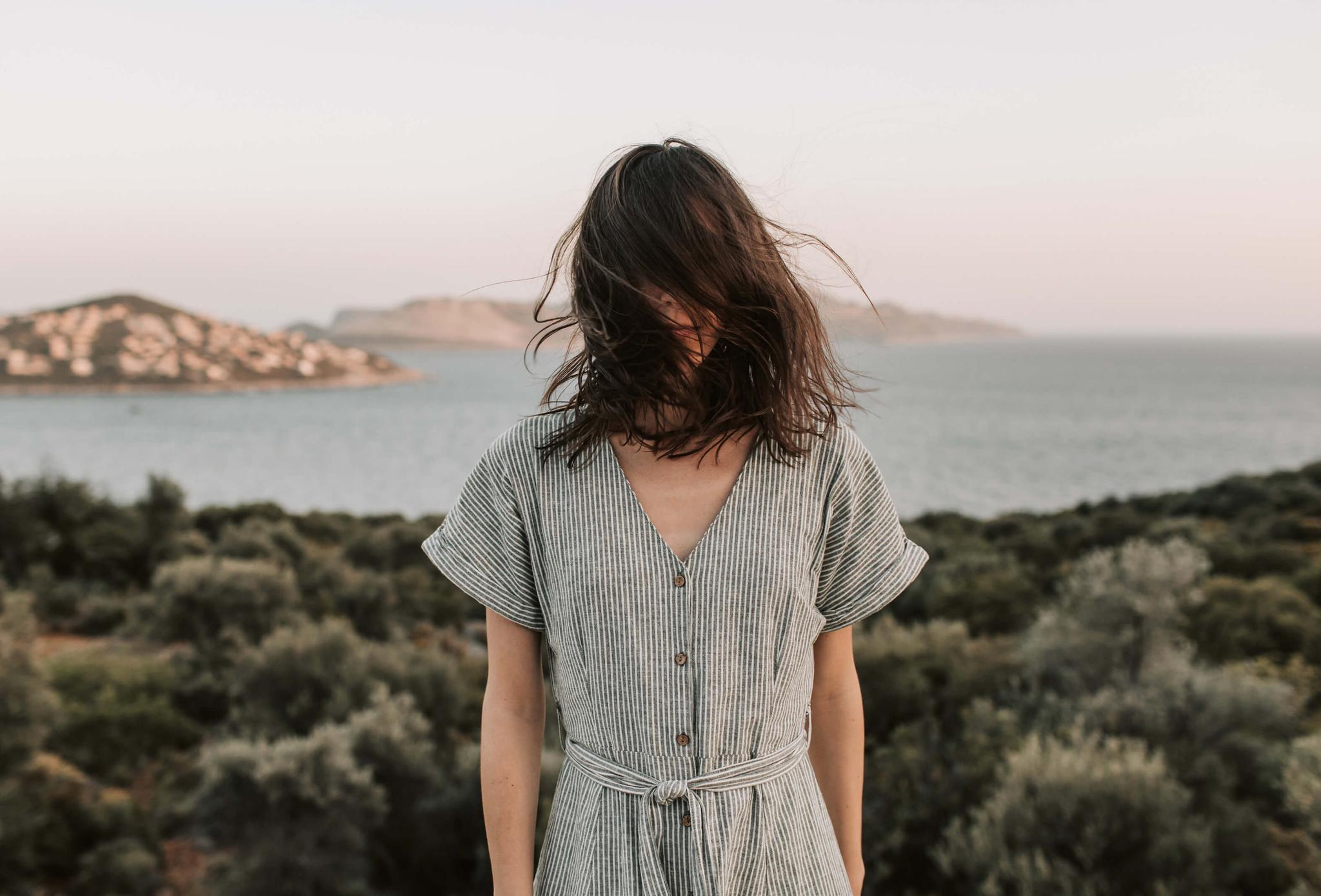 A person with their hair covering their face, representing feelings of depression.