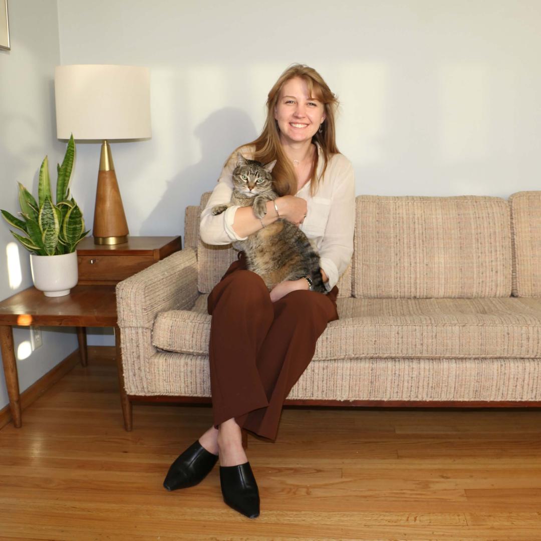 A picture of a licensed therapist, Siri Peterson, smiling while holding her brown tabby cat named jack