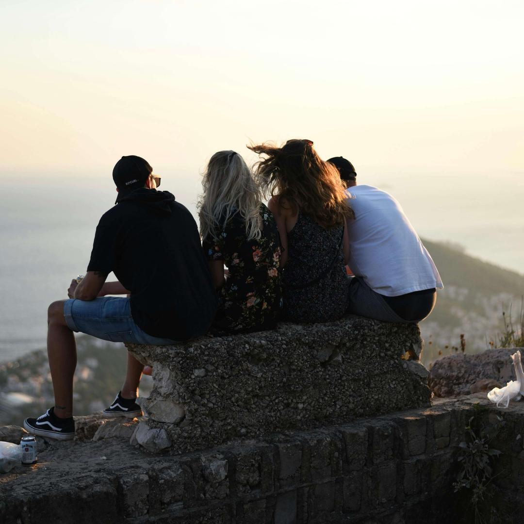 A group of friends sitting on a wall looking for the ocean