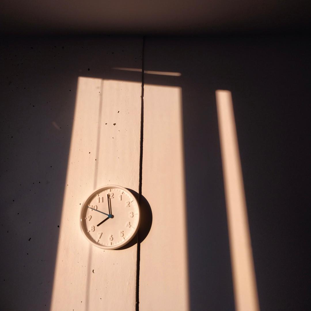 A clock on a wall with shadows