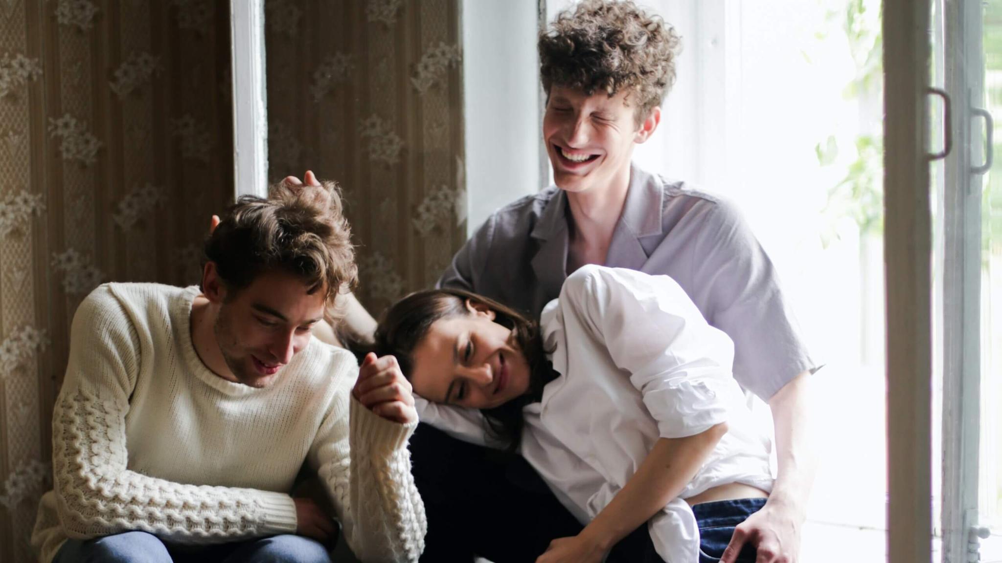 Polyamorous relationship of two men and a woman sitting in nook enjoying each others company